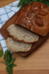 Top view of Baked homemade round bread cut in slices with nettles on wooden table with fresh nettle plants