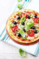 Pizza with salami, jalapeno pepper and black olives. Home made food. Concept for a tasty and hearty meal. Close up.	