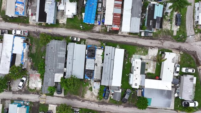 Rundown, damaged mobile homes in trailer park. Florida housing after severe hurricane, tropical storm damage. Aerial top down orbit shot.