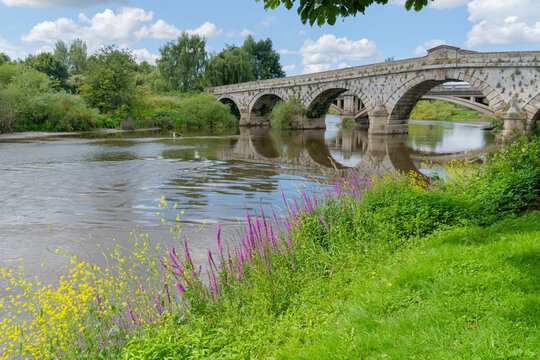 Atcham bridge from the banks of the fast flowing River Severn in Atcham, Shropshire, UK on a summer's day in landscape orientation