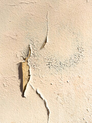 Cracked beige paint on the wall of a house. Abstract background