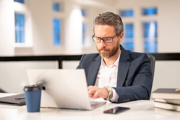 Middle aged businessman working with laptop in office. Hispanic business man using laptop....