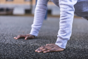 Hands of african man doing push-ups on the floor. Close-up view