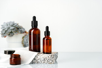 Amber Glass Dropper Bottles on Stone Platform With Succulents