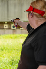 A determined female athlete, known for her precision and skill in sports shooting, aims her rifle with focus and intensity during a competitive event, embodying strength and concentration