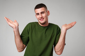 Fototapeta premium Young Man Wearing Green T-Shirt Gesturing With Both Hands in Front of a Plain White Background