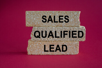 Sales Qualified Lead symbol. Concept words Sales Qualified Lead on the brick blocks. Beautiful red background. Business and SQL concept.