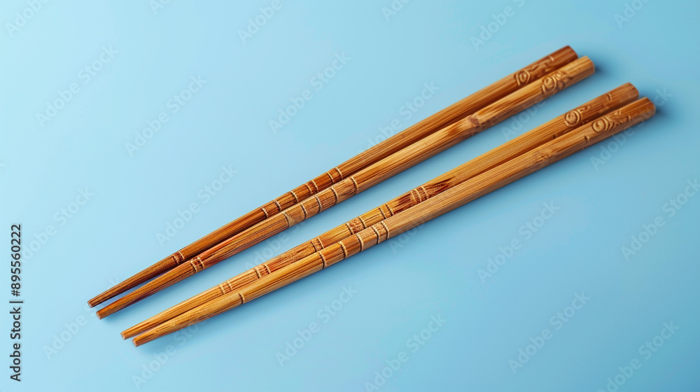 Poster a set of bamboo chopsticks with detailed engravings isolated on a light blue background with ample c