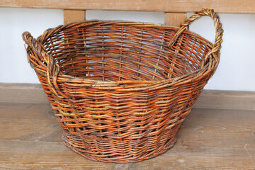 Fototapeta premium Retro straw basket on a wooden bench. Vintage container in cottage kitchen. Country life.