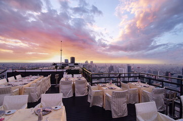 Table setting on roof top restaurant with megalopolis view, Bangkok Thailand.