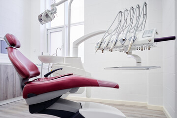 Dental equipment in dentist office in new modern stomatological clinic room. Background of dental chair and accessories used by dentists in red and white