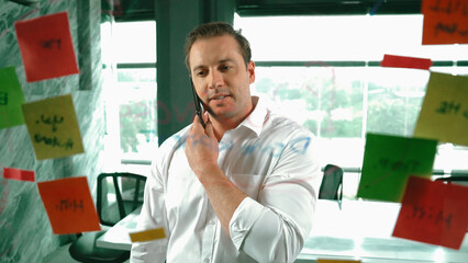 Professional businessman making phone call to customers while looking at marketing strategy idea...