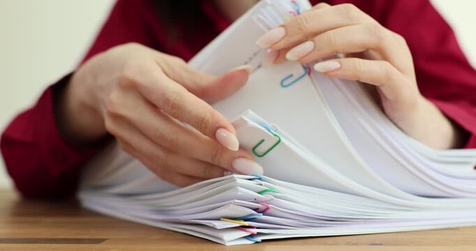 Young woman secretary examines large stack of papers