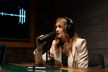 A young woman is hosting a podcast in a modern studio, speaking into a microphone
