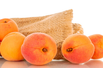 Several ripe apricots with jute bag, macro, isolated on white background.
