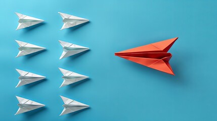 A red paper airplane stands out among white ones, soaring in a new path against a blue backdrop