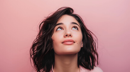 Woman with hopeful expression looking upwards on pastel background