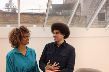 Smiling man and woman standing and talking in modern creative studio