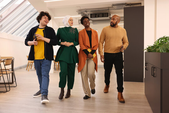 Multiethnic creative team members smiling and walking in modern office