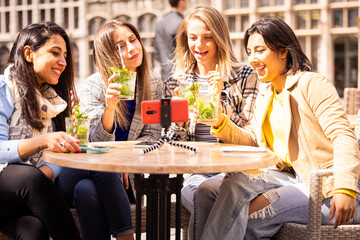 Having a great time, four friends shoot a summer video at a cafe, enjoying drinks and each others company in the city