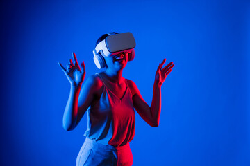 Smart female standing surrounded by neon light wearing VR headset connecting metaverse, future...