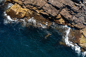 top view of the sea waves beating against the rocky shore