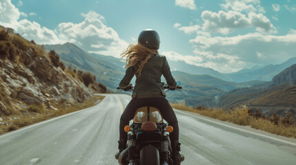 A woman riding a motorcycle on a scenic mountain road.