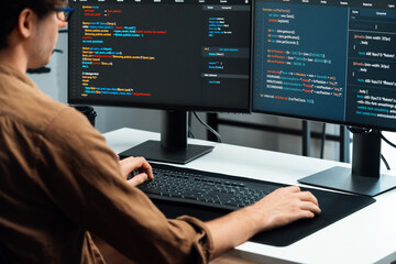 IT developer working online software development on pc monitors at modern home office on coding...