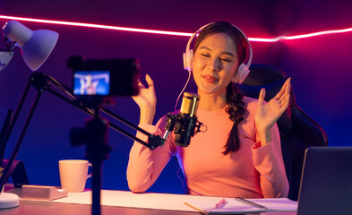 Host channel of creative broadcast listening the music on social media with listeners in positive podcast, wearing pastel color headphones, using mic radio record by camera at neon studio. Stratagem.