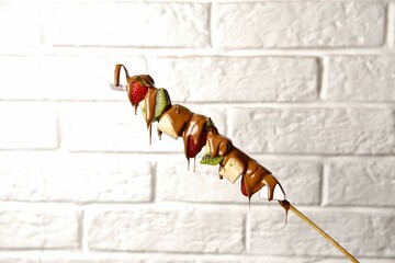 Chocolate Covered Fruit Skewer on White Brick Wall