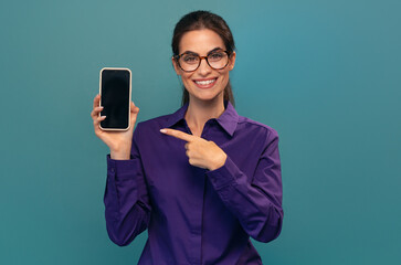 Attractive woman holding smartphone posing in front of camera on isolated blue
