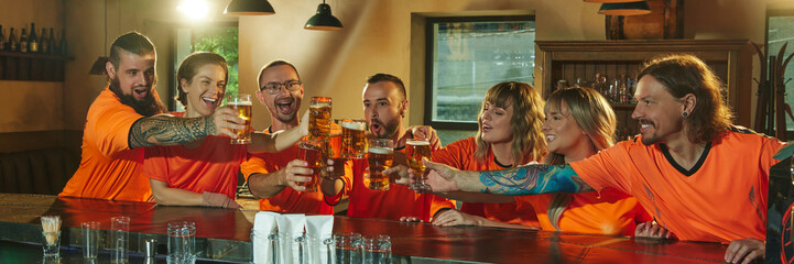 Banner. Group of people happily, joyfully clinking glasses with beer at bar, in moment of celebration win of favorite soccer team. Concept of friendship, soccer fan, championship, support. Ad