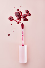 Abstract splashes of lip gloss tint sample and brush, vertical format