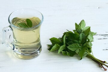 Herbal tea made from  Aegopodium podagraria, commonly called ground elder or bishop´s weed on white wood table. Herbal tea used in traditional medicine for painful joints.