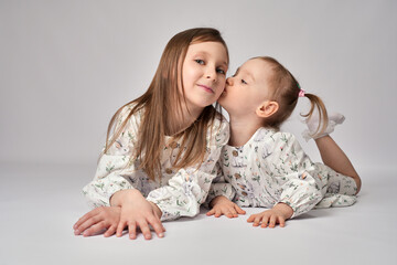 A portrait of two sisters on a white background with copy space. Happy children having fun together.