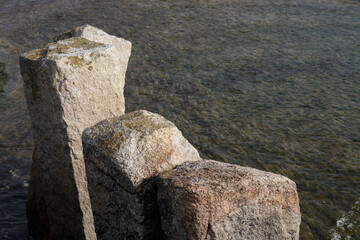 Old historical beige stone pier posts in sea