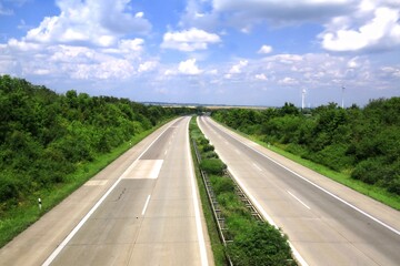 Empty German Autobahn surrounded by greenery and cloudy sky