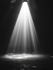 A bright spotlight shines down on a rough concrete floor in a dark room