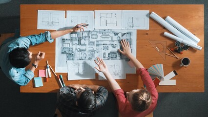 Group of people looking at blueprint while brainstorming idea. Top view of engineer team looking...