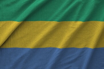 Gabon flag depicted on folded wavy fabric of old cloth close up