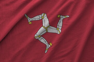 Isle of Man flag depicted on folded wavy fabric of old cloth close up