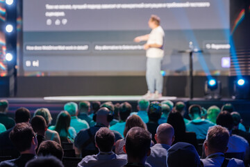 Speaker giving a presentation at a business conference. Engaged audience watching a professional speaker on stage.