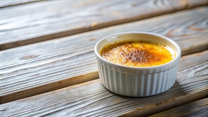 Crème brûlée en un ramekin blanco sobre una mesa de madera en un entorno rústico. Postre clásico de la cocina francesa. Espacio libre para texto.