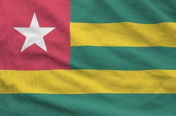 Togo flag depicted on folded wavy fabric of old cloth close up