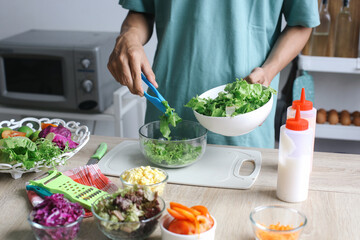 Man Making Salad, Putting Sliced Lettuce Leaf Into Bowl For Salad Ingredient Mixup