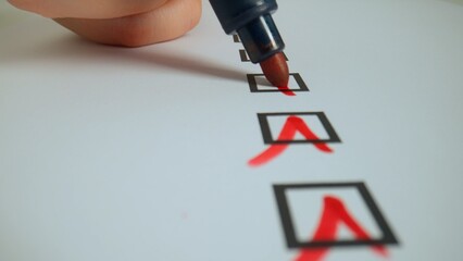 Close up shot of woman hand working with document, red marker in female hand writing check marks in...