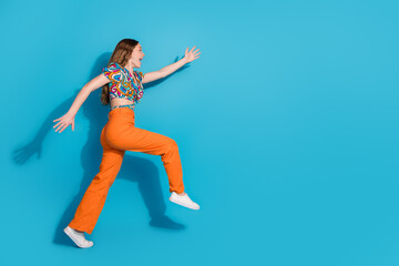 Full size photo of nice young girl run empty space wear top isolated on blue color background