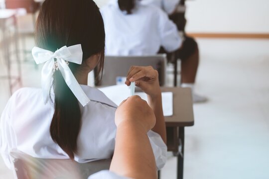 Students secretly take notes and send answers to each other during a school exam. Concept of corruption in the exam room.