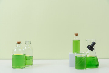 Assorted Laboratory Glassware with Green Liquid on White Surface