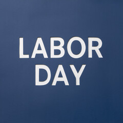 The phrase ‘Labor Day’ created using negative space, with each letter cut out of a solid color background, showcasing elegant minimalism